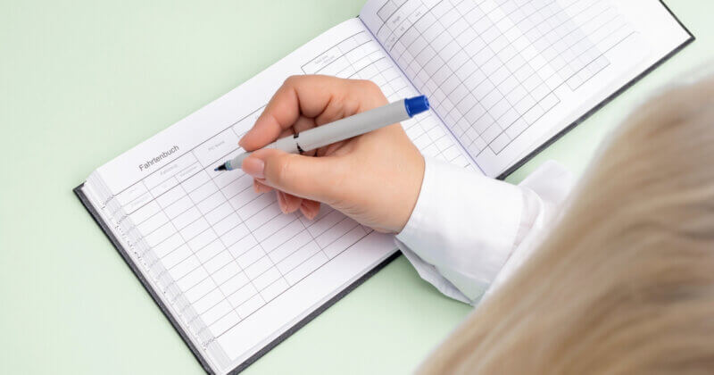 Frau die per Hand Fahrtenbuch ausfüllt Lexware